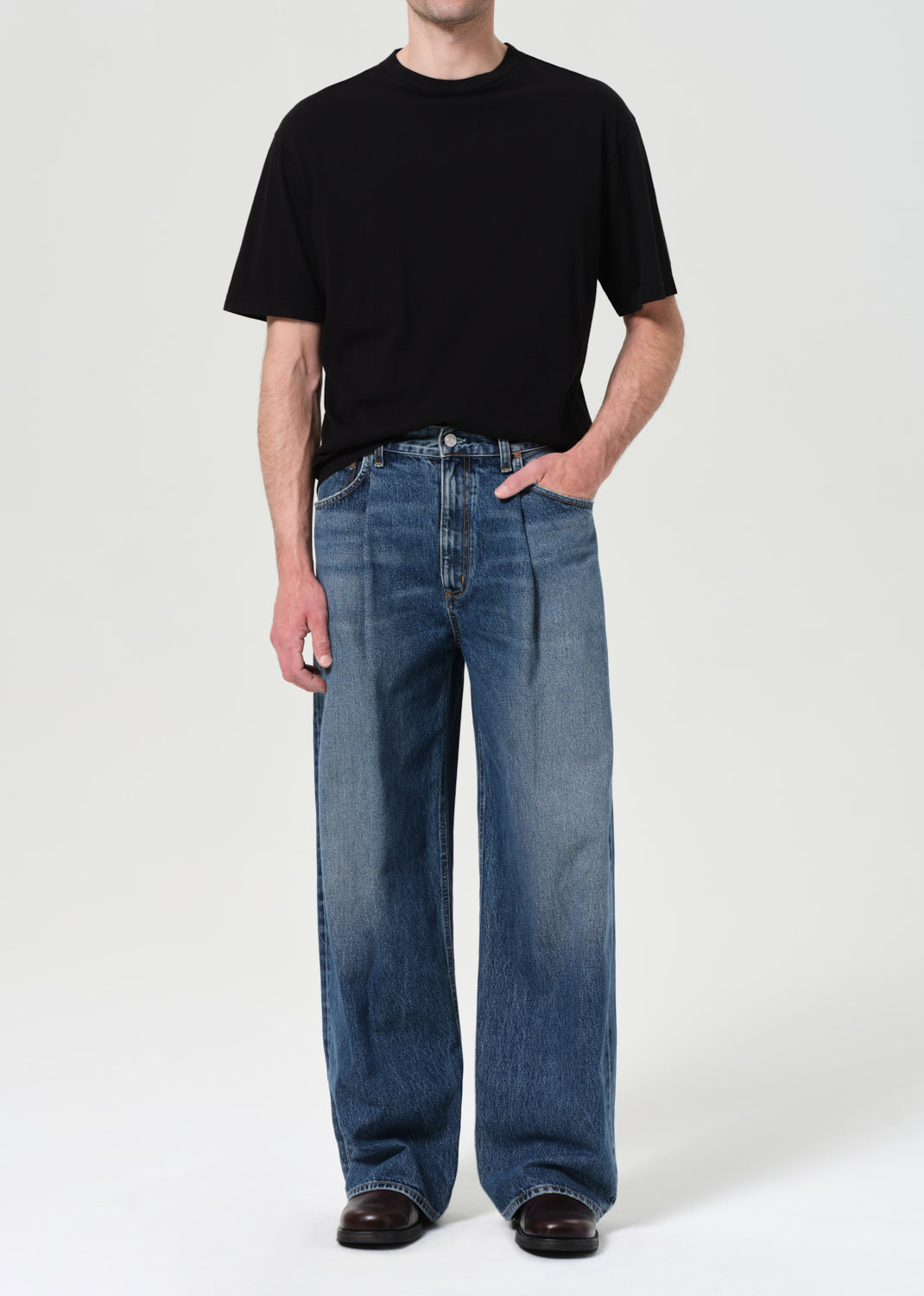 Person wearing a black t-shirt and blue jeans on a white background