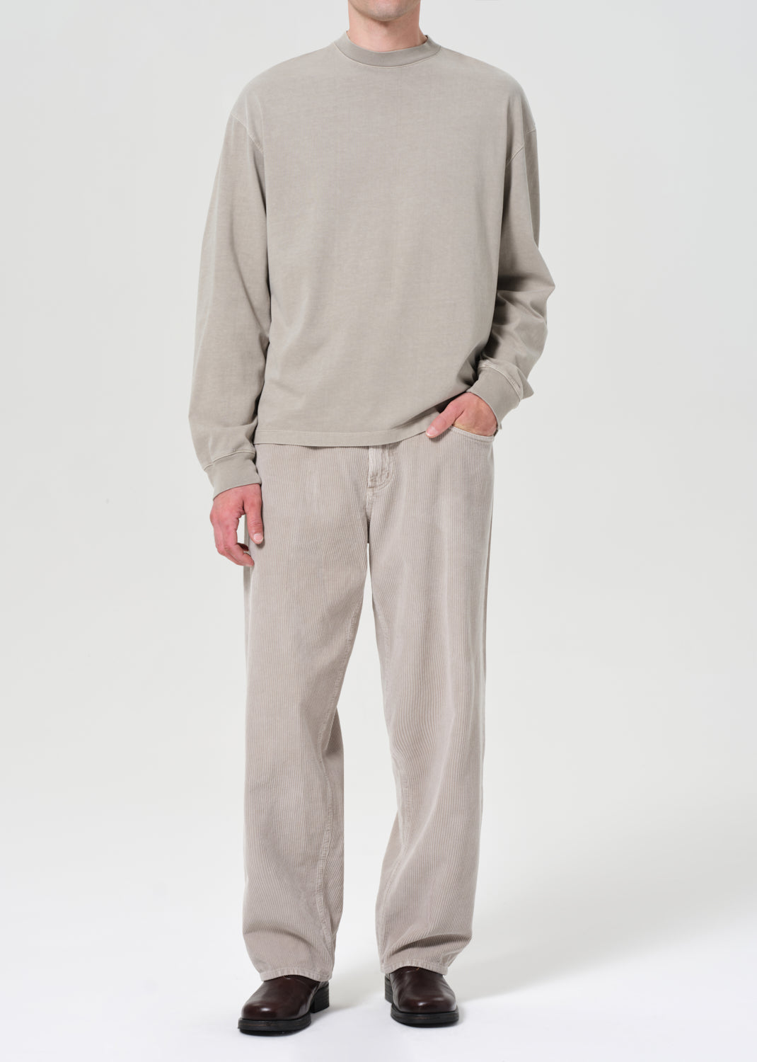 Person wearing a beige sweater and pants on a white background