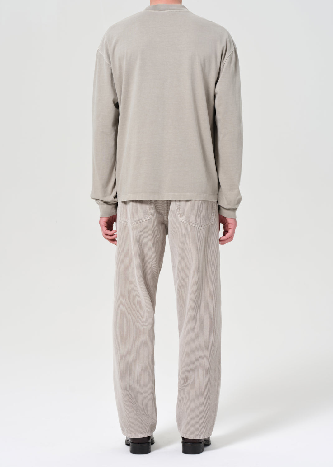 Person wearing a beige long-sleeve top and pants on a white background