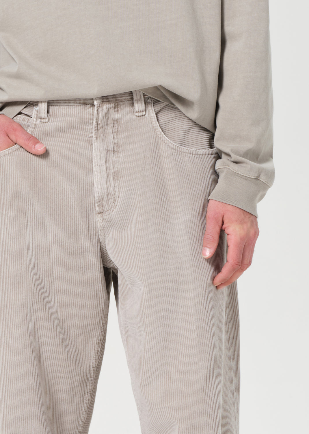 Person wearing light gray corduroy pants and a matching shirt on a white background