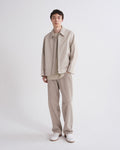 Person wearing a beige outfit with a jacket and pants on a white background