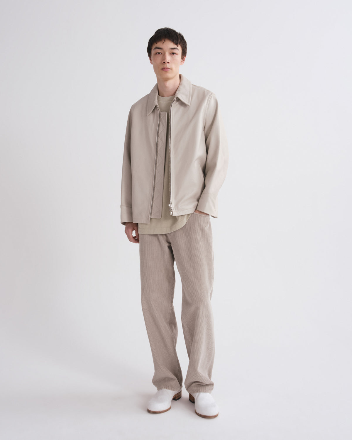Person wearing a beige outfit with a jacket and pants on a white background