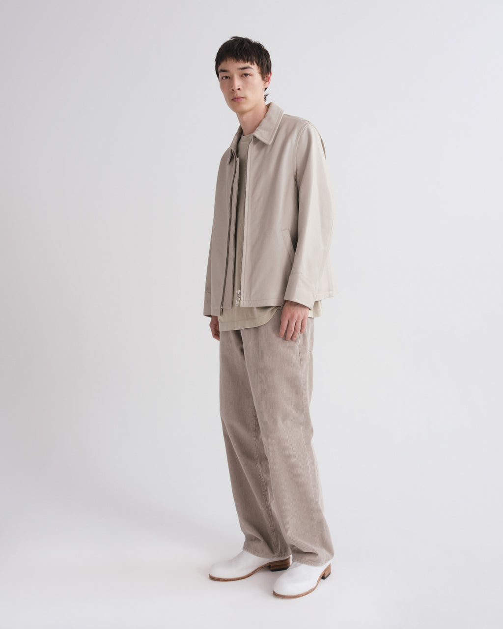 Person wearing a beige outfit with a white background