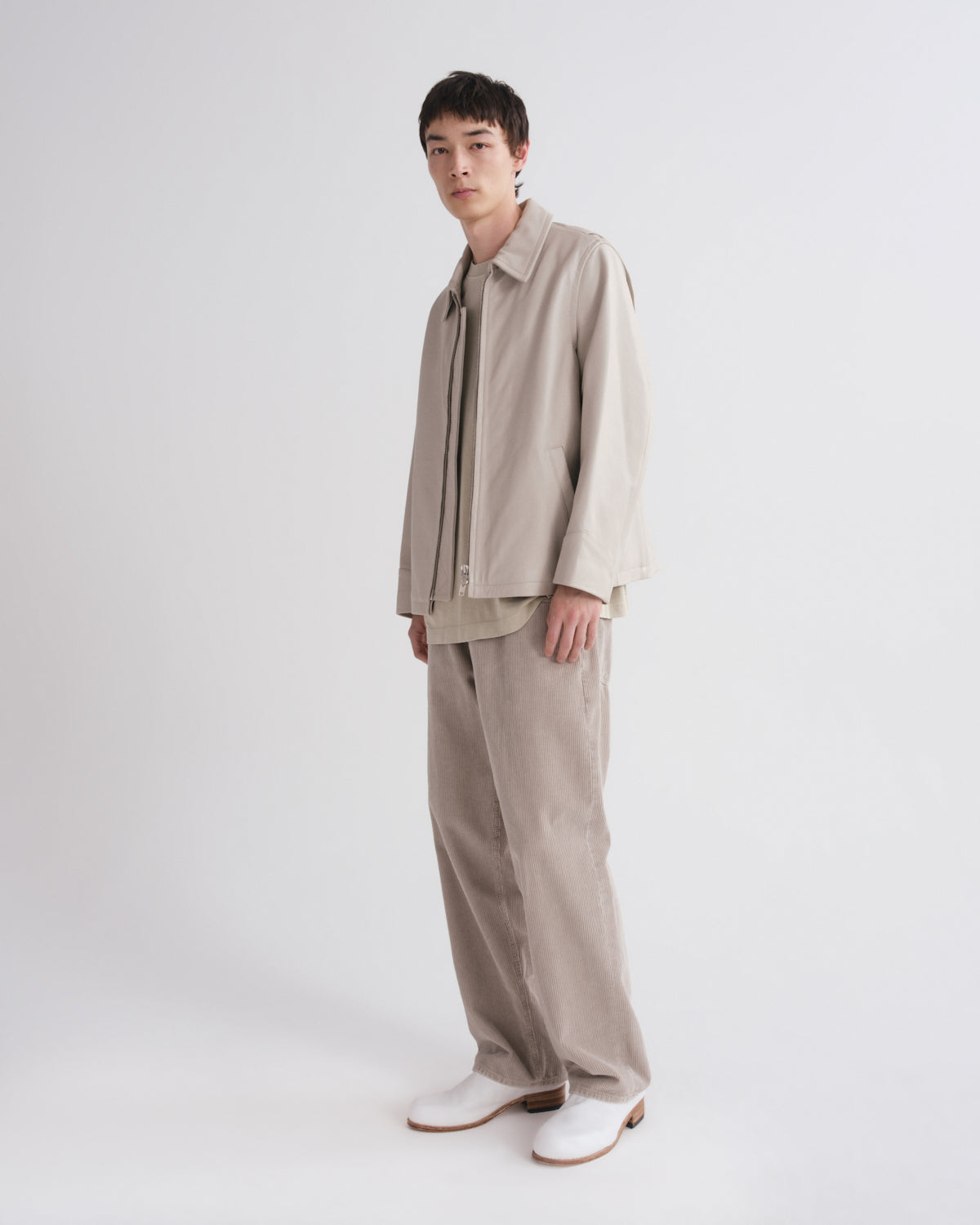 Person wearing a beige outfit with a white background