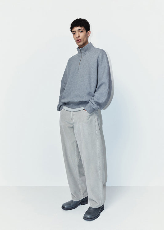 Person wearing a gray sweater and pants on a white background