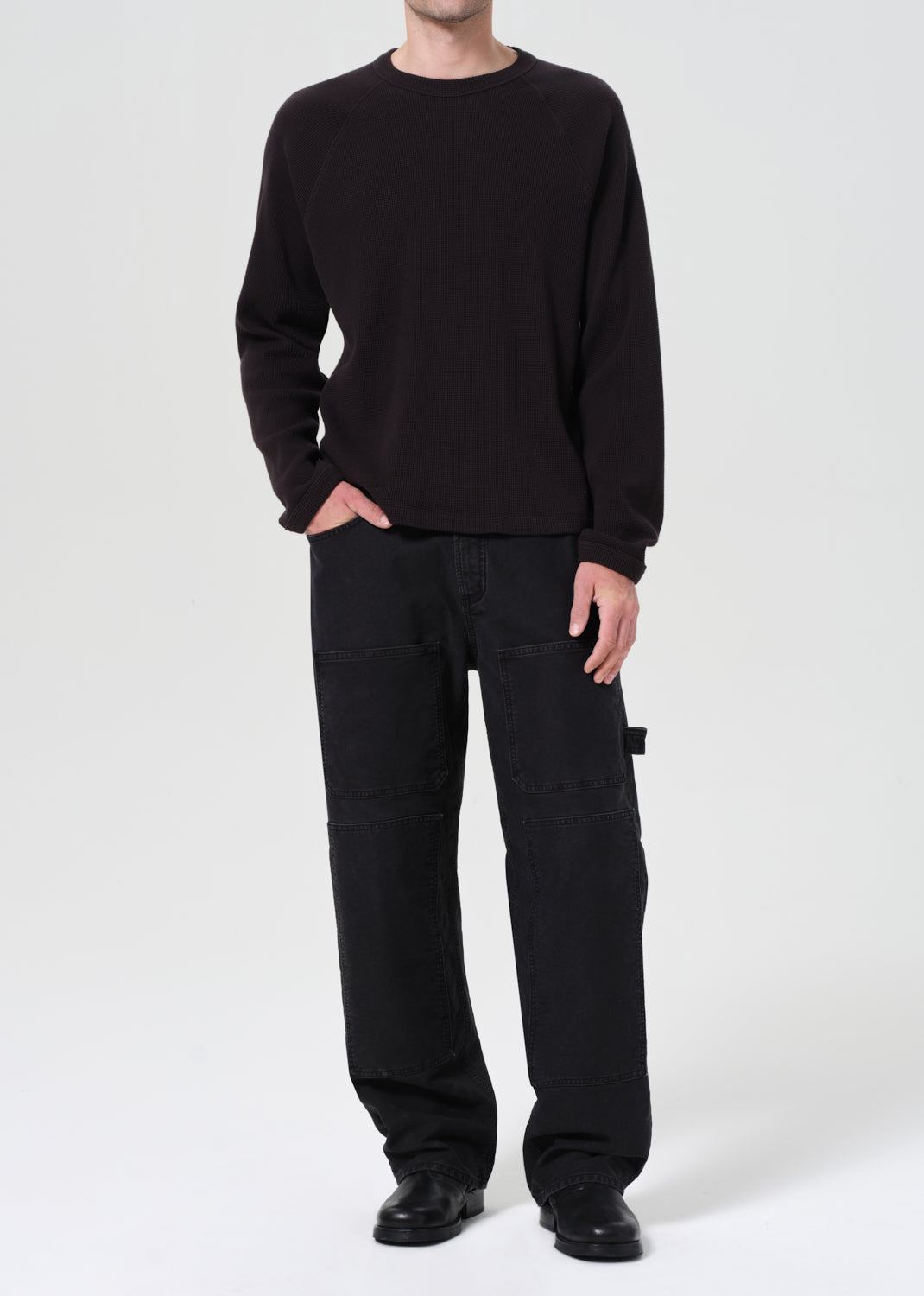 Person wearing a black sweater and black pants on a white background