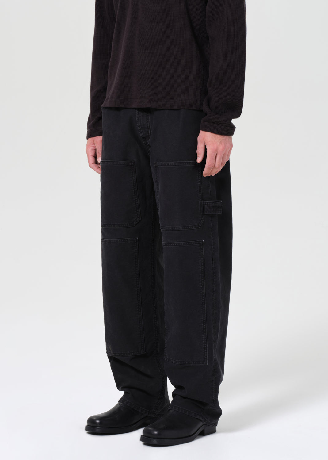 Person wearing black cargo pants and a black shirt on a white background