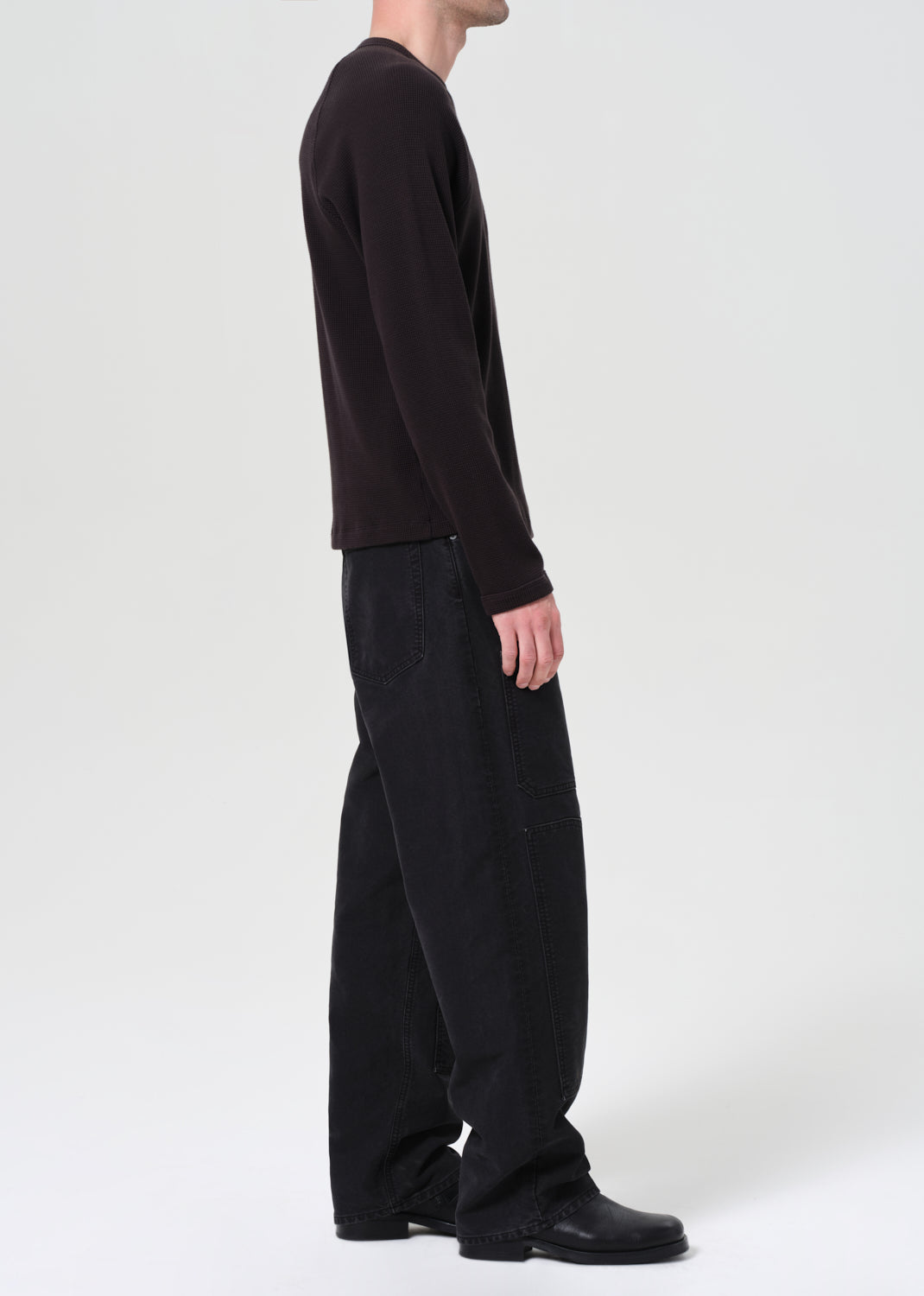 Person wearing a black long-sleeve shirt and pants on a white background