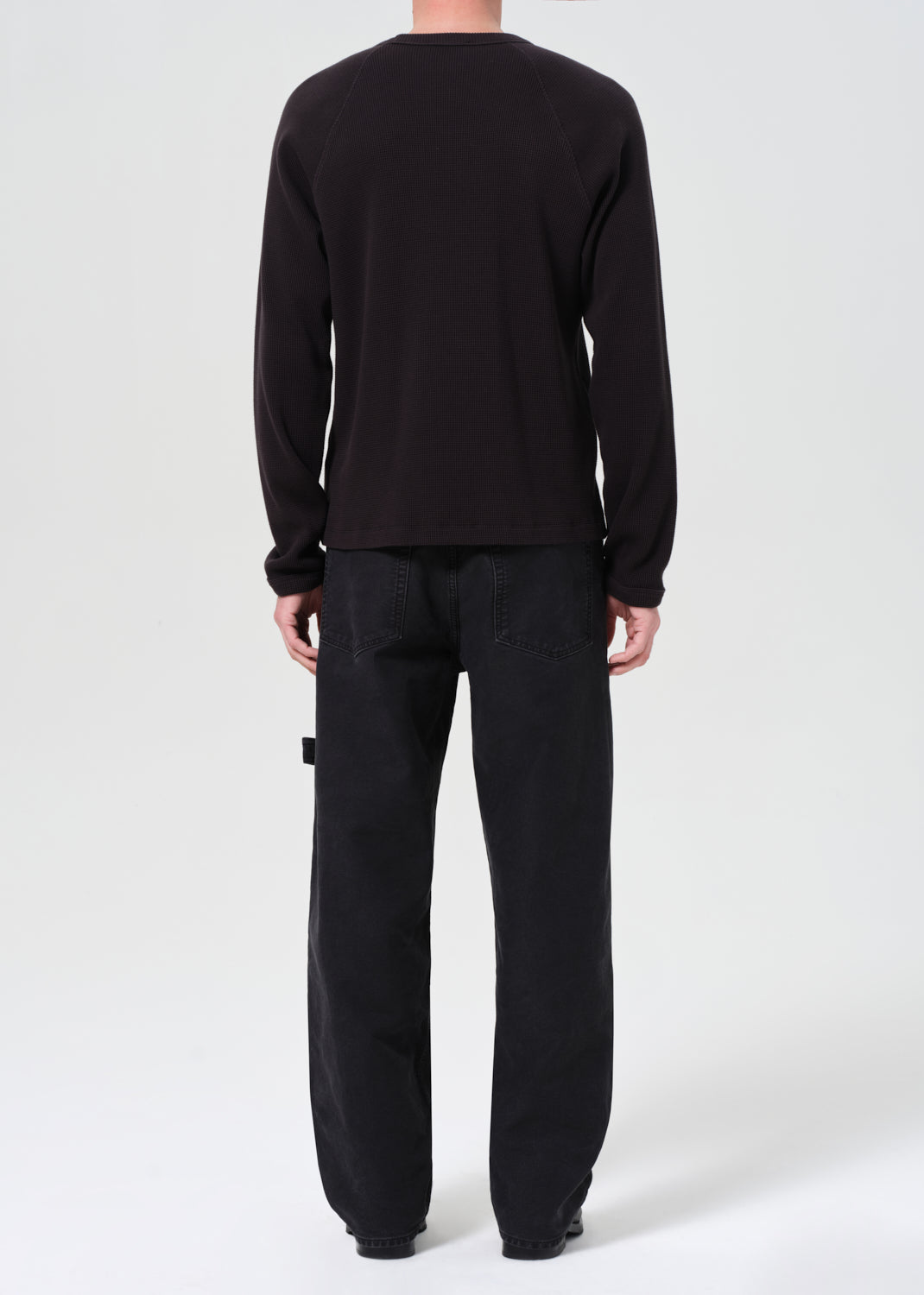 Person wearing a black long-sleeve shirt and pants on a white background
