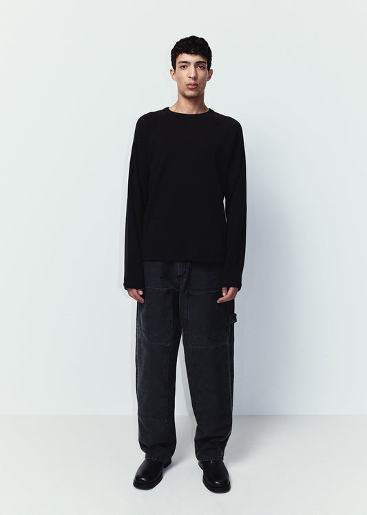 Man wearing a black sweater and pants standing against a white background