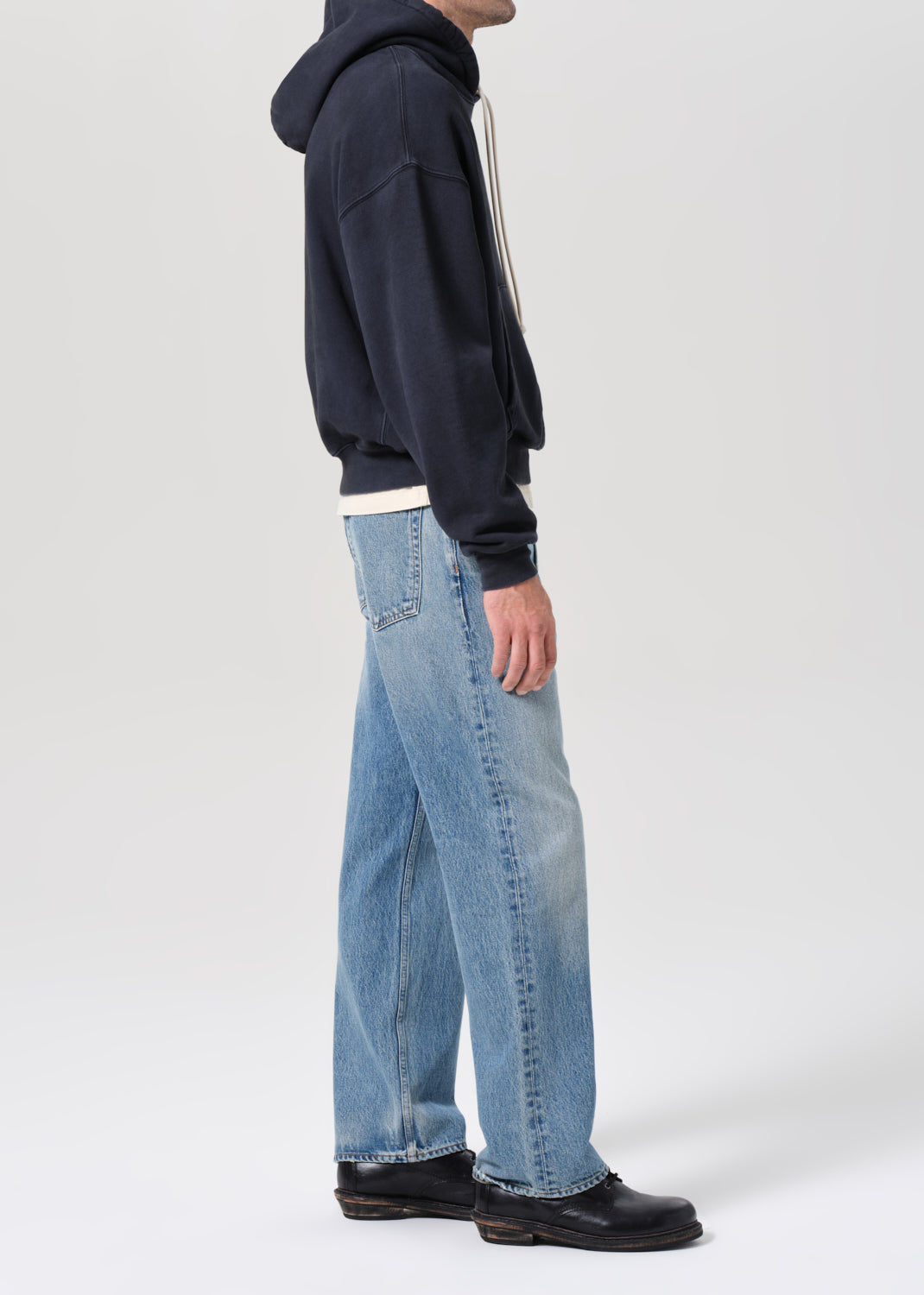 Person wearing a navy hoodie and light blue jeans on a white background