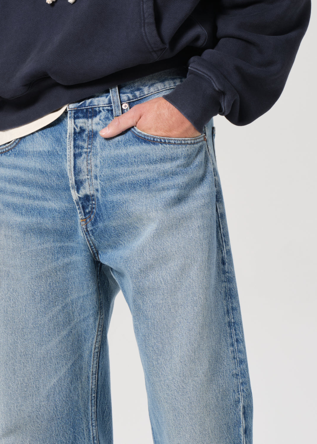 Person wearing blue jeans with a neutral background