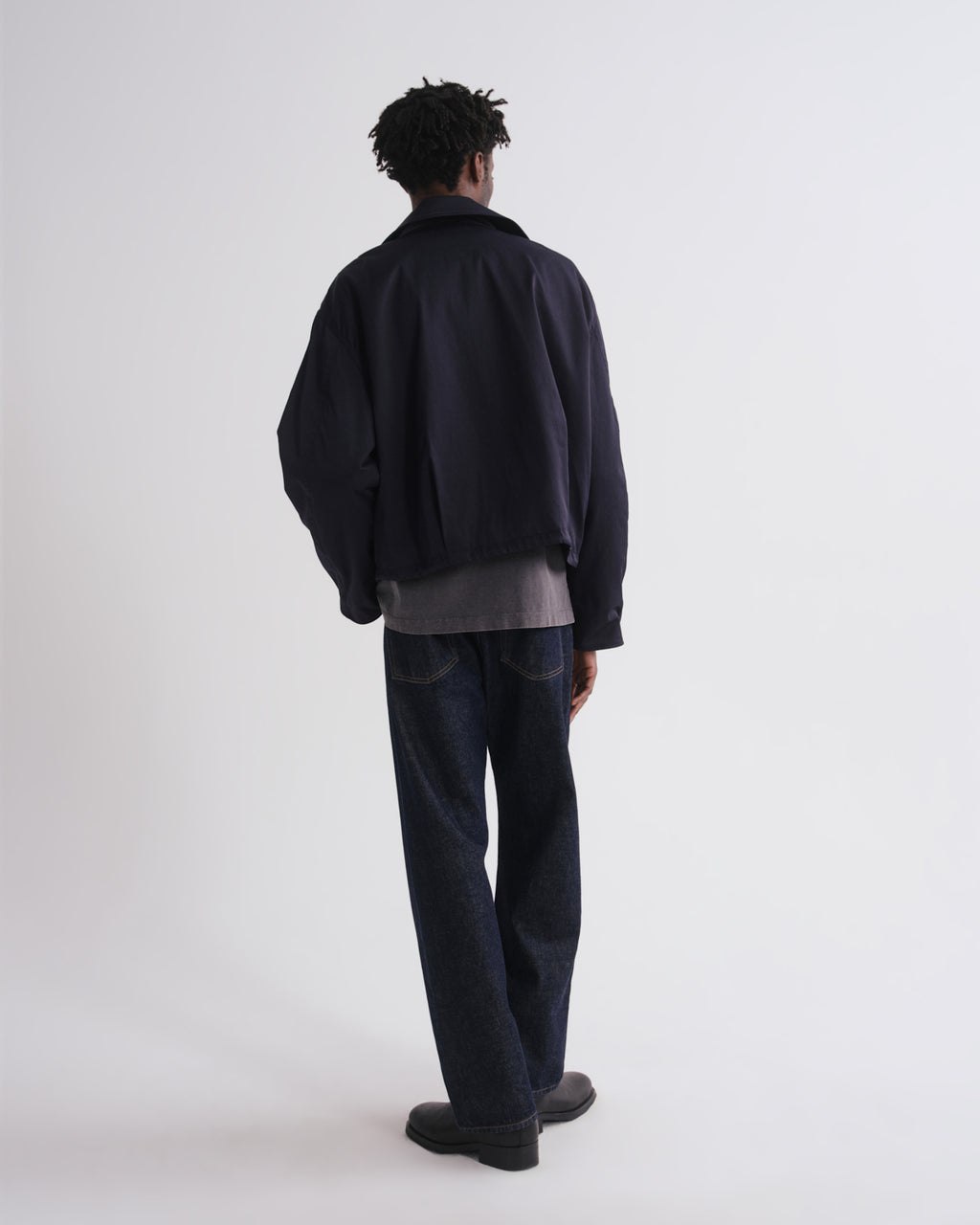 Person wearing a black jacket and dark pants on a white background