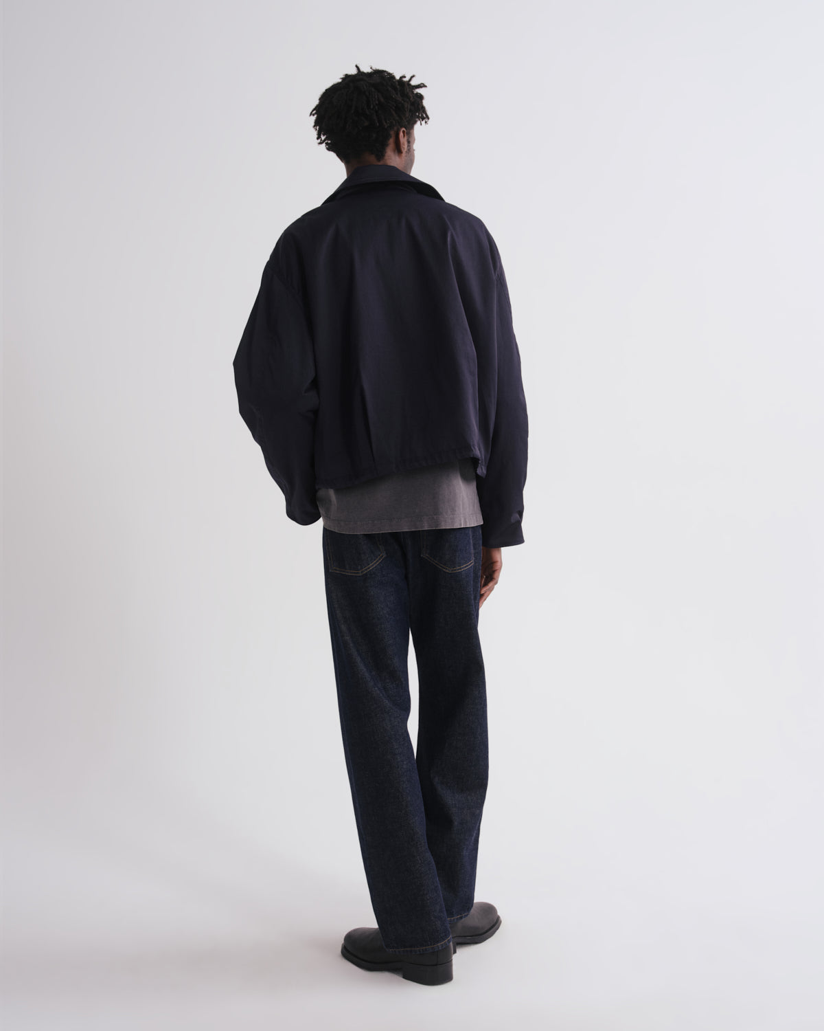 Person wearing a black jacket and dark pants on a white background