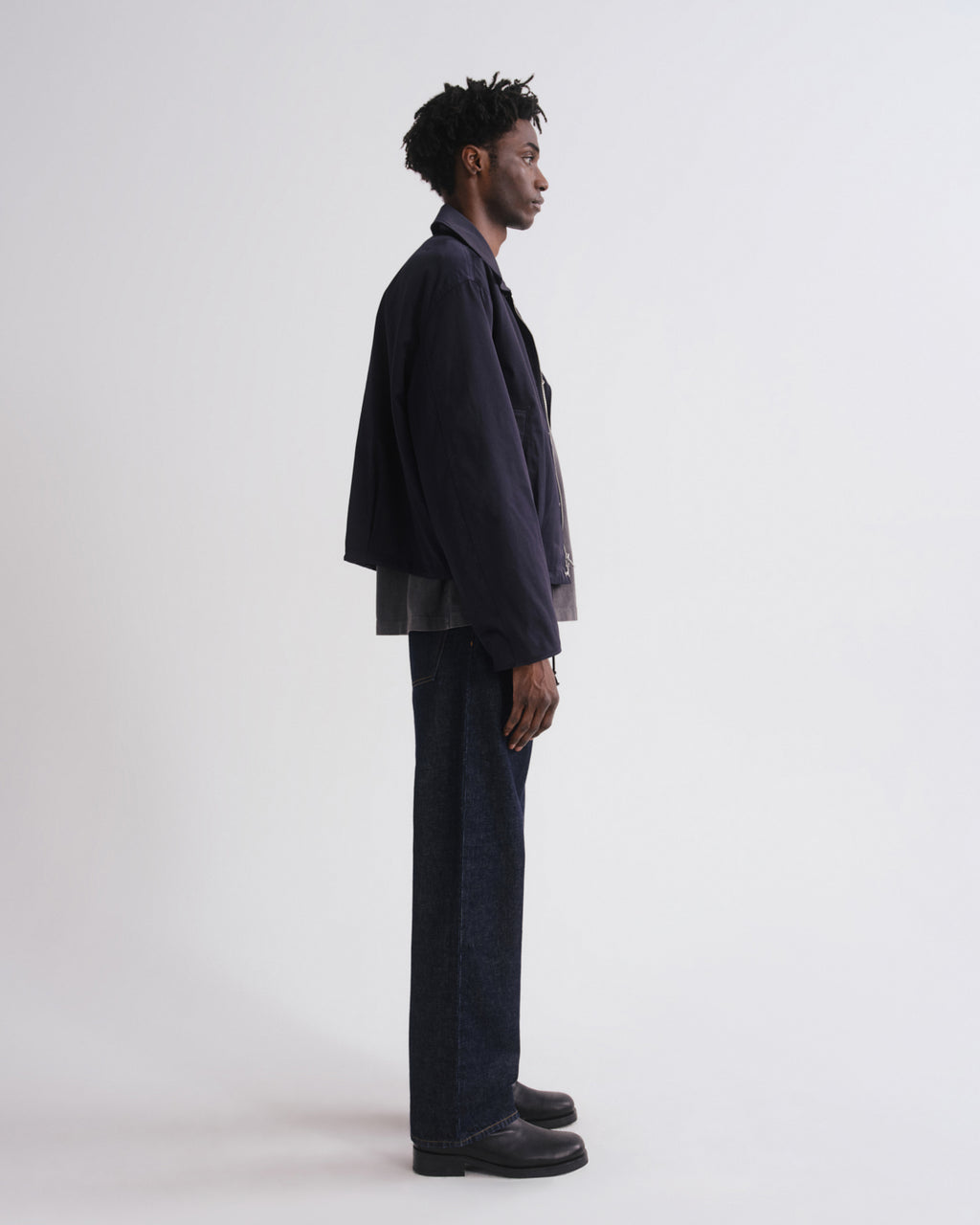 Person wearing a dark suit standing against a white background