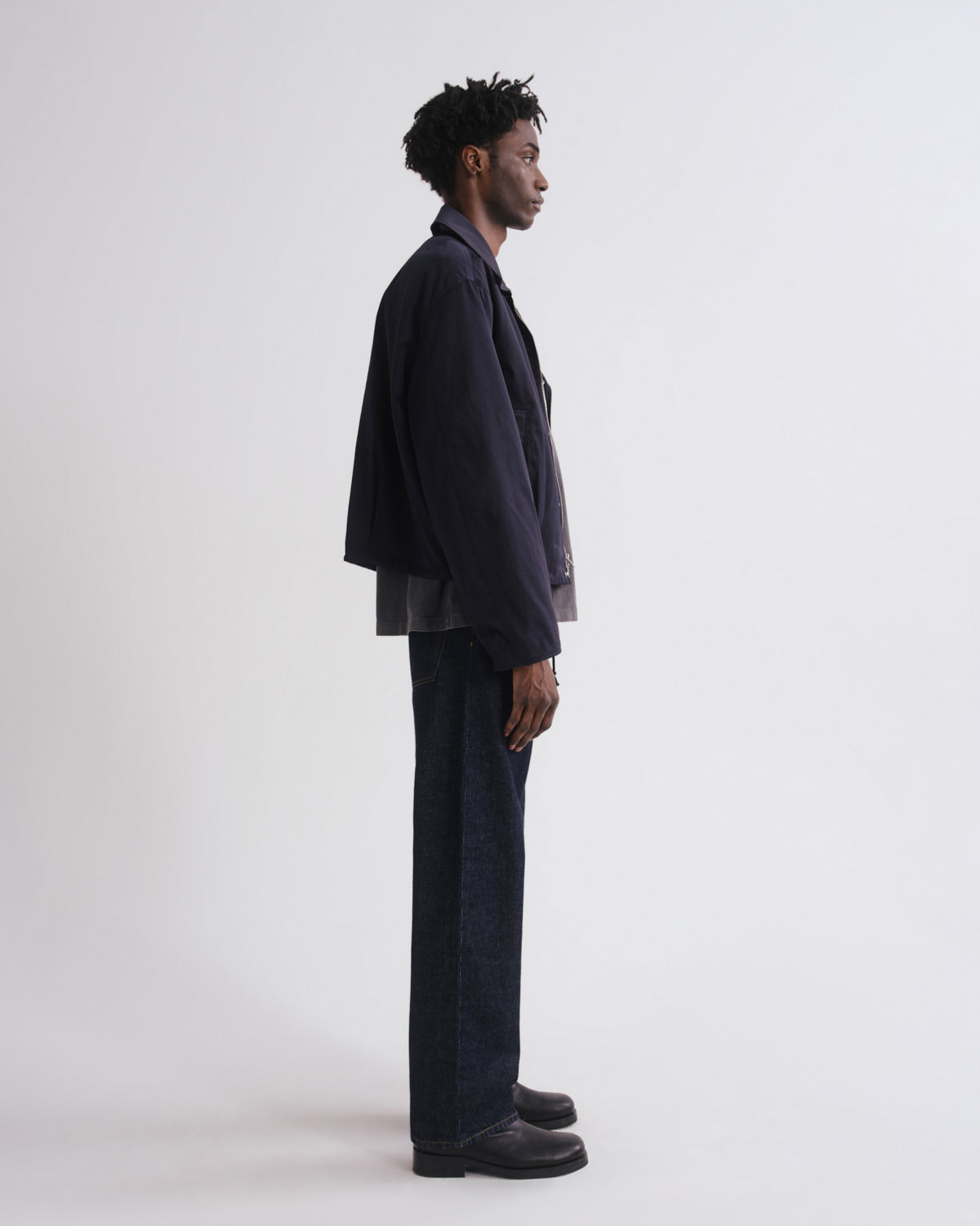Person wearing a dark suit standing against a white background