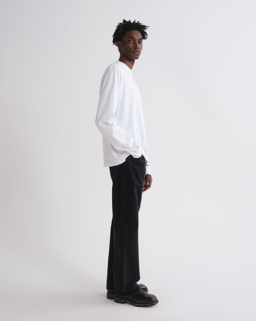 Person wearing a white shirt and black pants on a white background