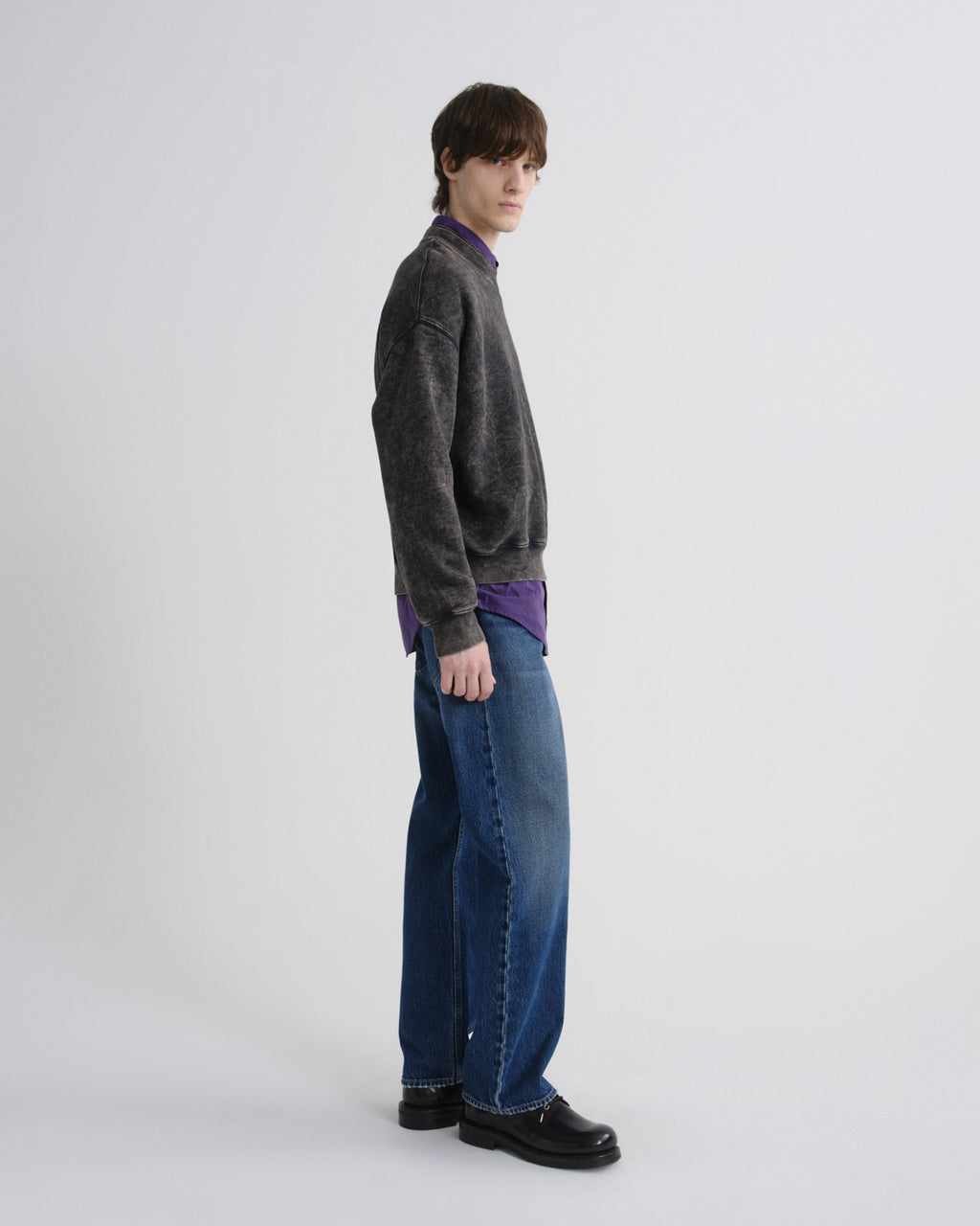 Person wearing a gray sweater and blue jeans on a white background