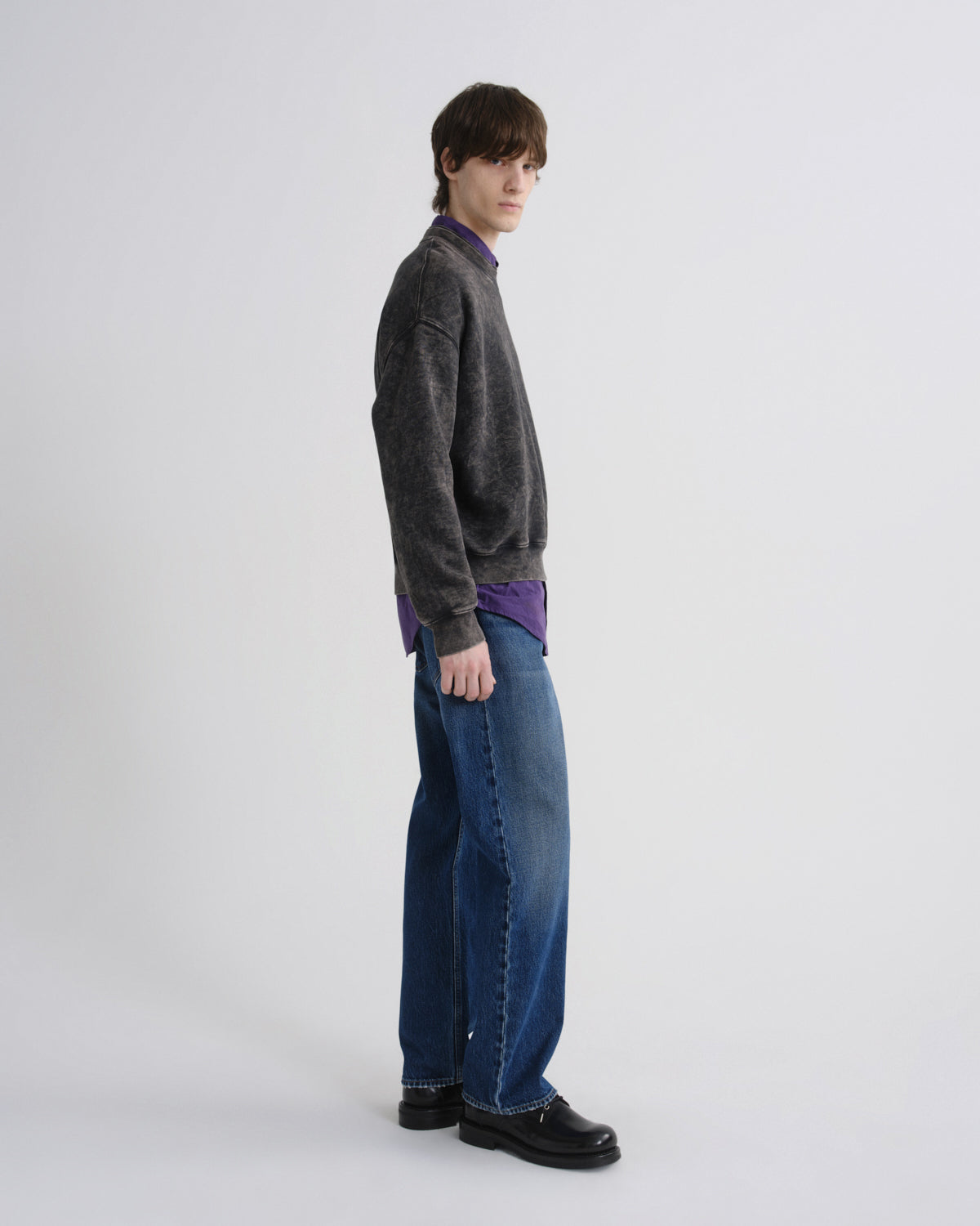 Person wearing a gray sweater and blue jeans on a white background