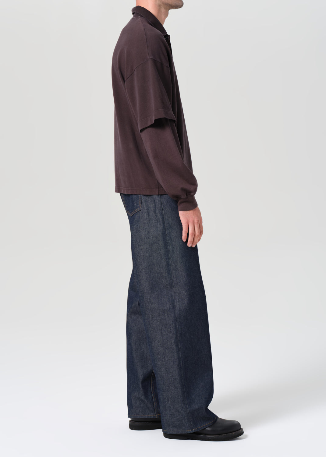 Person wearing a brown shirt and dark blue wide-leg pants on a white background