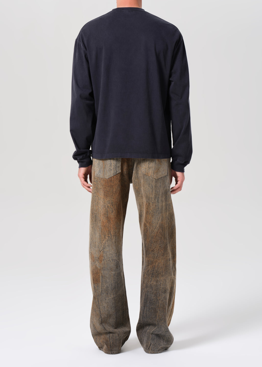 Person wearing a dark long-sleeve shirt and brown patterned pants on a white background