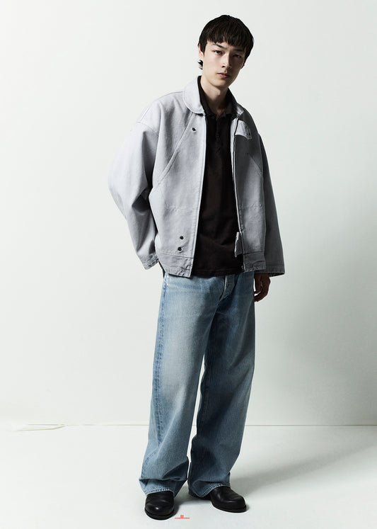 Person wearing a gray jacket and light blue jeans on a white background