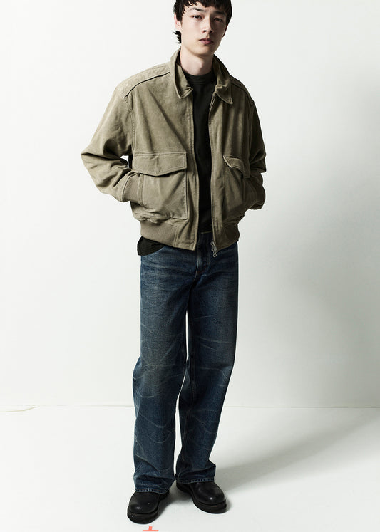 Person wearing a green jacket and blue jeans on a white background
