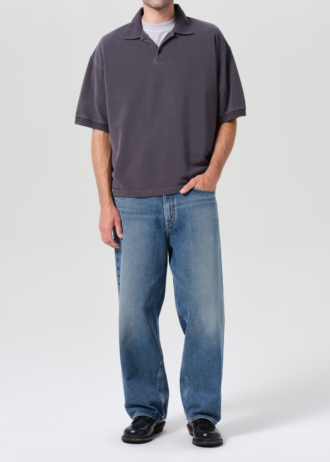 Person wearing a gray polo shirt and blue jeans on a white background