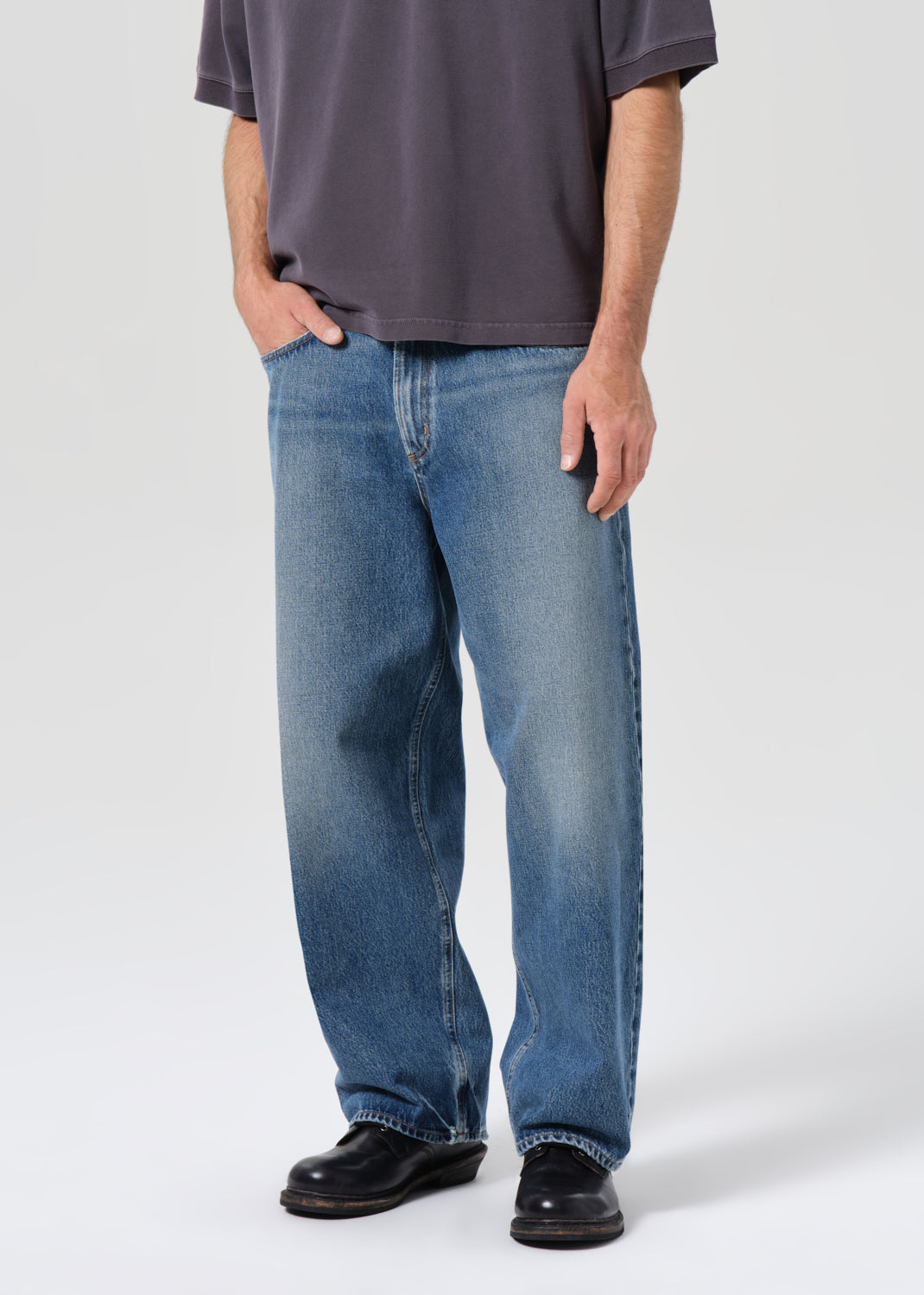 Person wearing blue jeans and a dark shirt on a white background