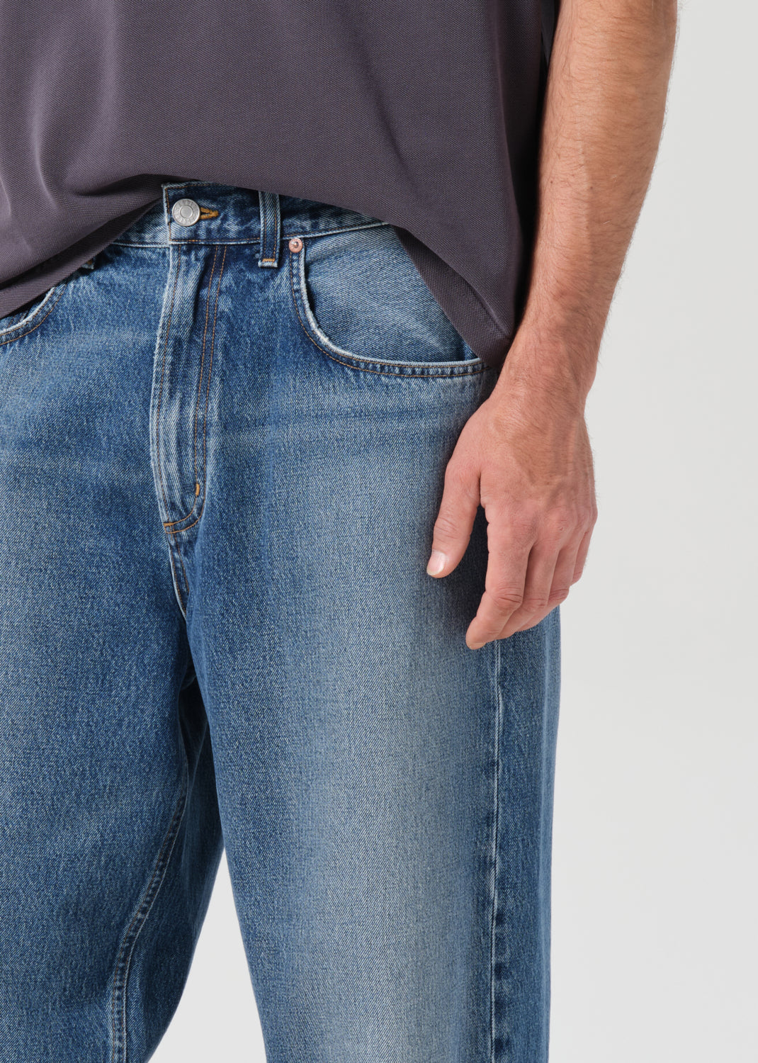 Person wearing blue jeans with a plain background