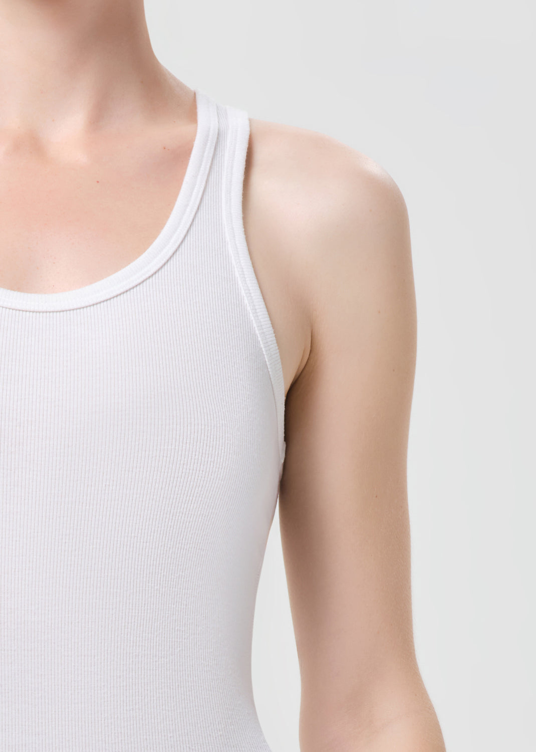 White tank top worn by a person on a light gray background