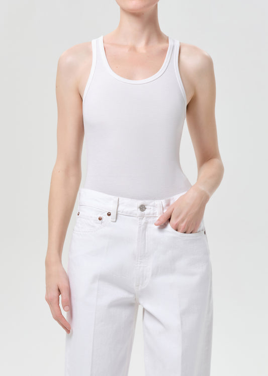 Person wearing a white tank top and white pants on a plain background