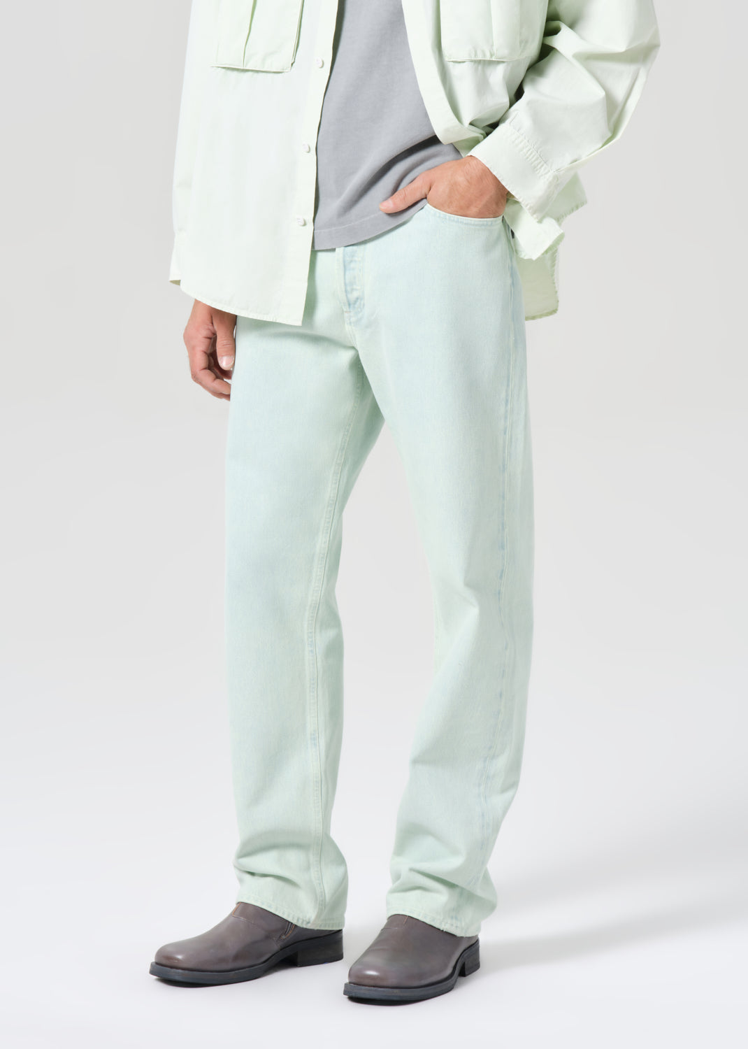 Person wearing light green pants and a white jacket on a plain background