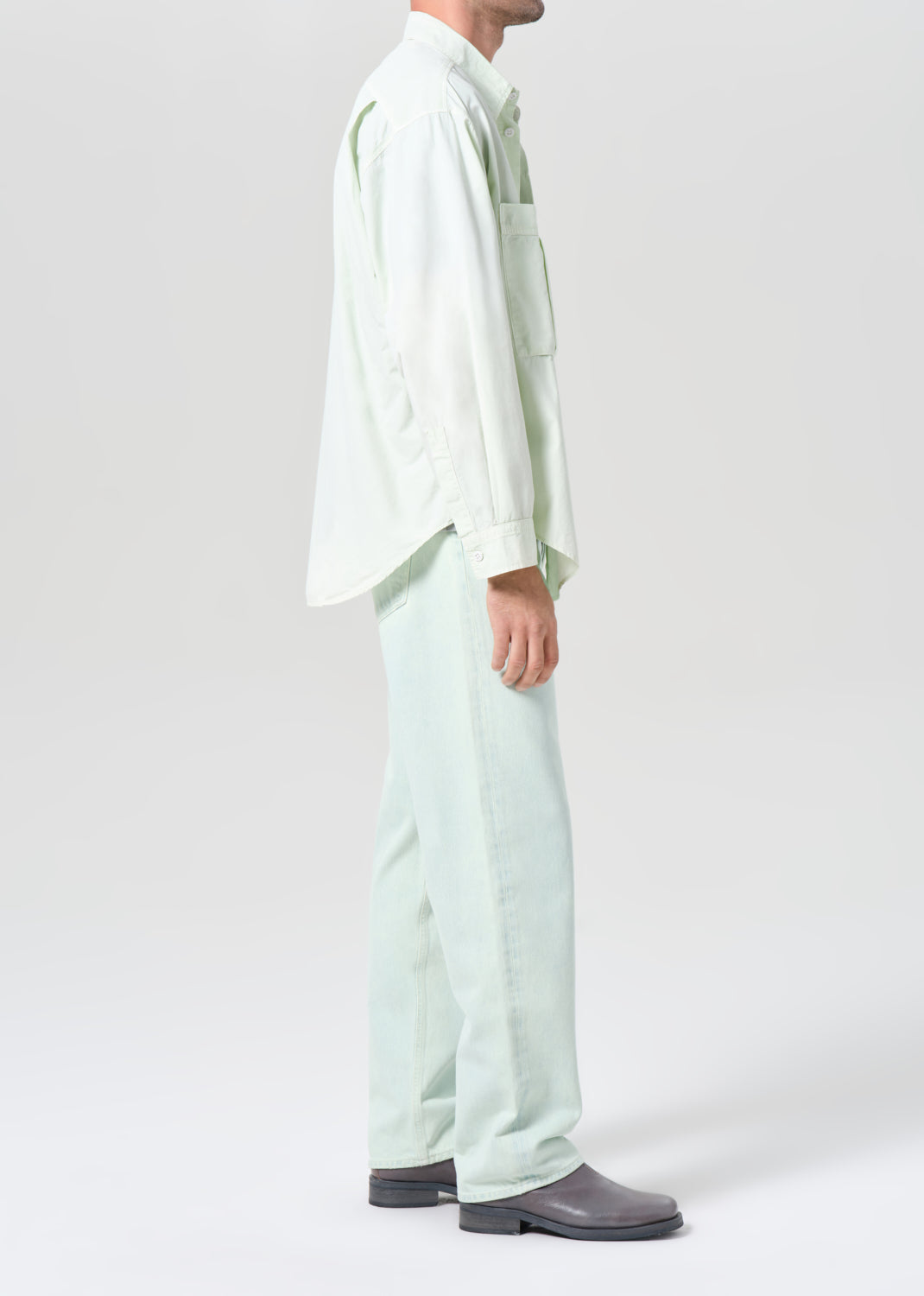 Person wearing a light green shirt and pants on a white background