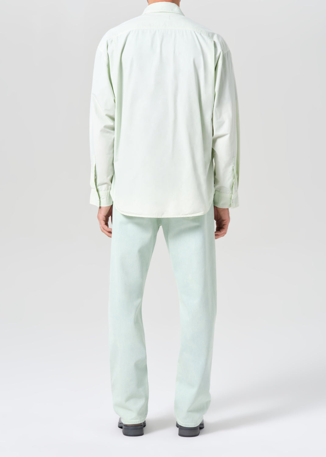 Person wearing a light green outfit on a white background
