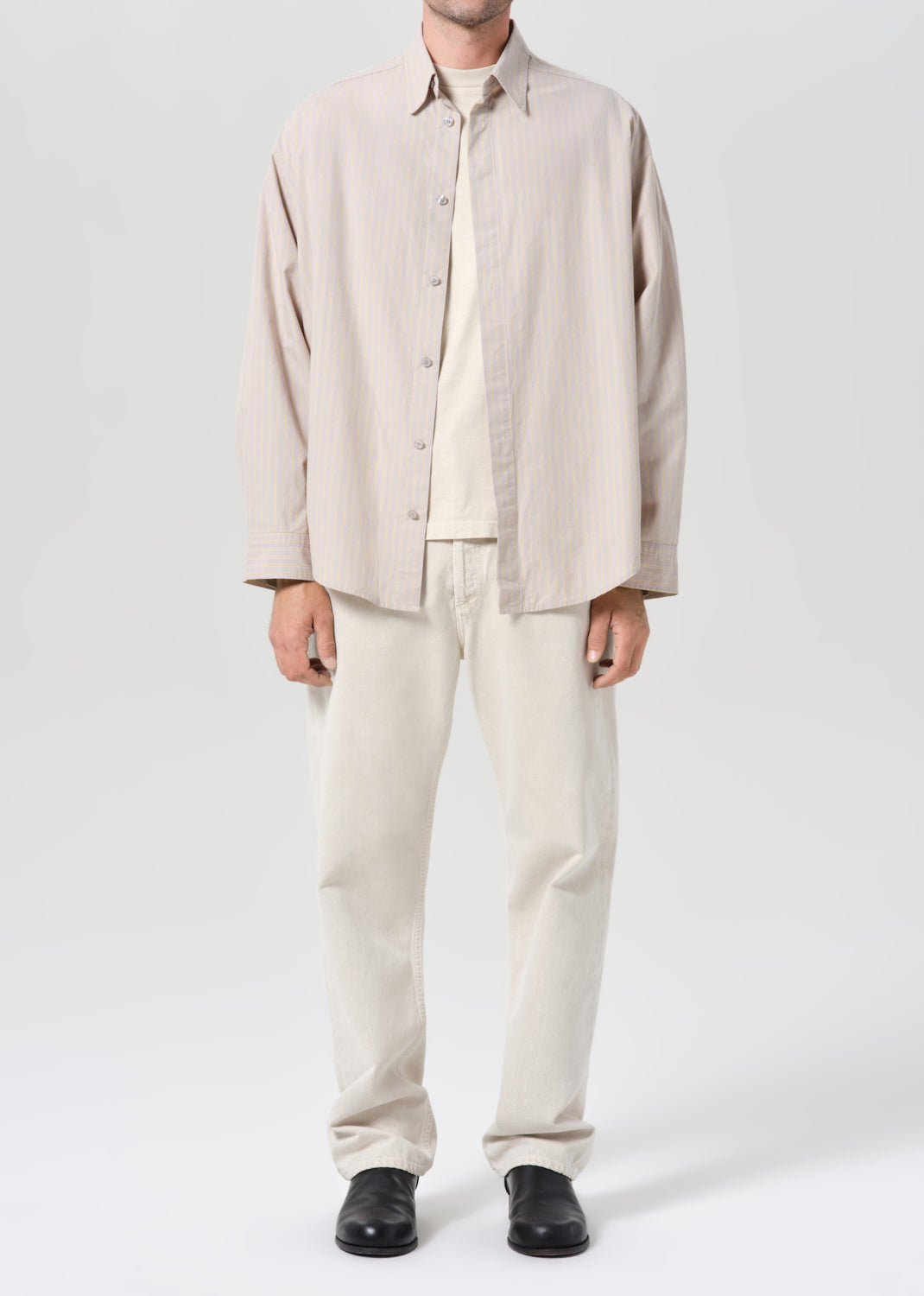 Person wearing a beige shirt and pants set on a white background