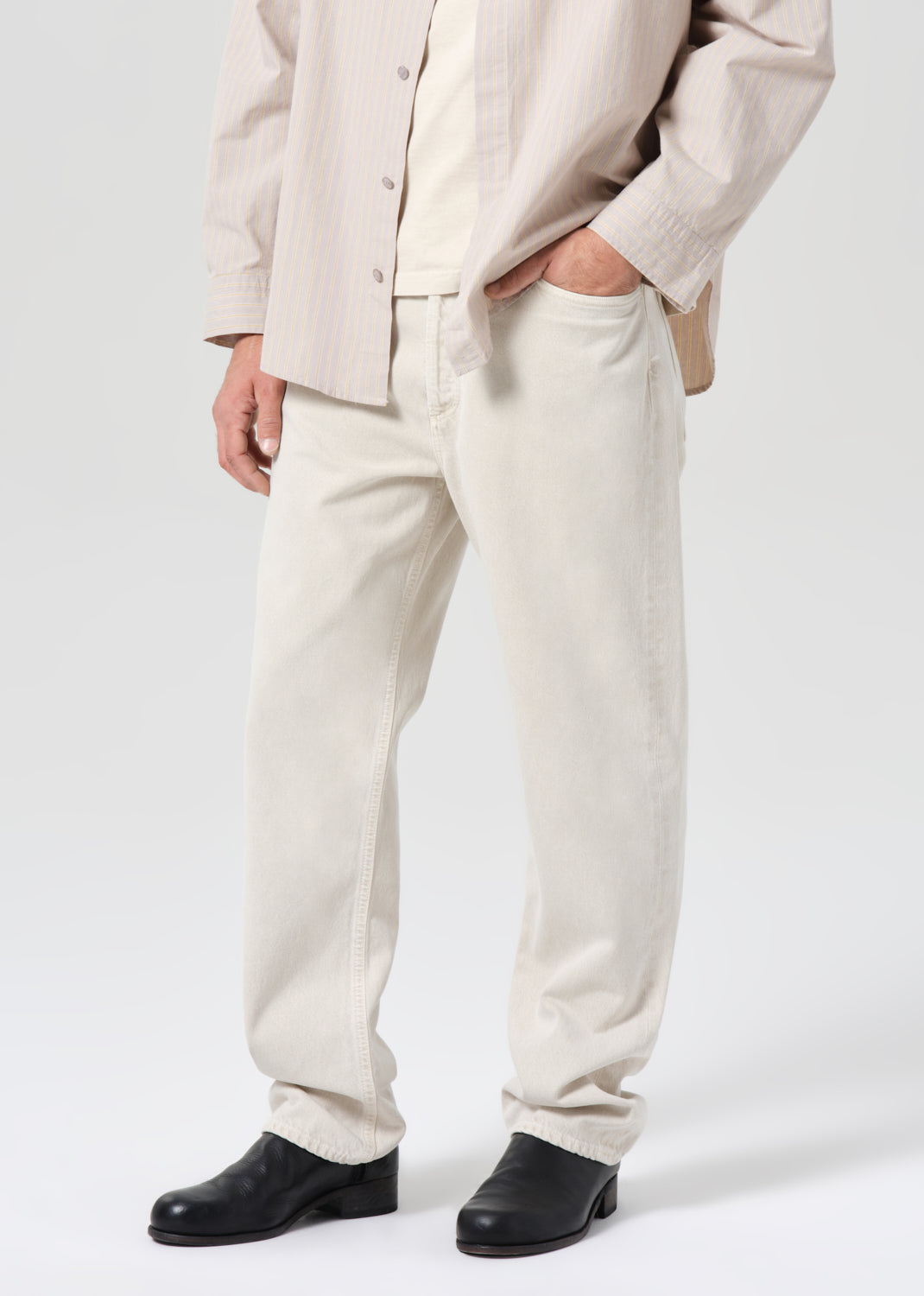 Person wearing a beige suit with black shoes on a white background