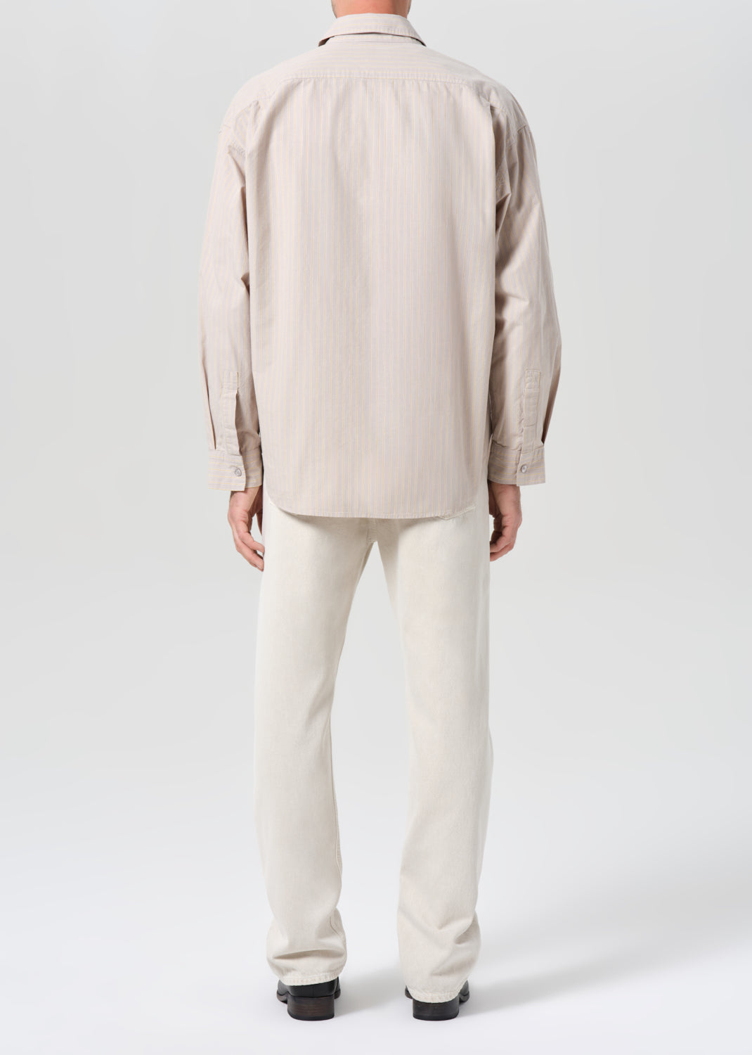 Person wearing a beige coat and pants on a white background