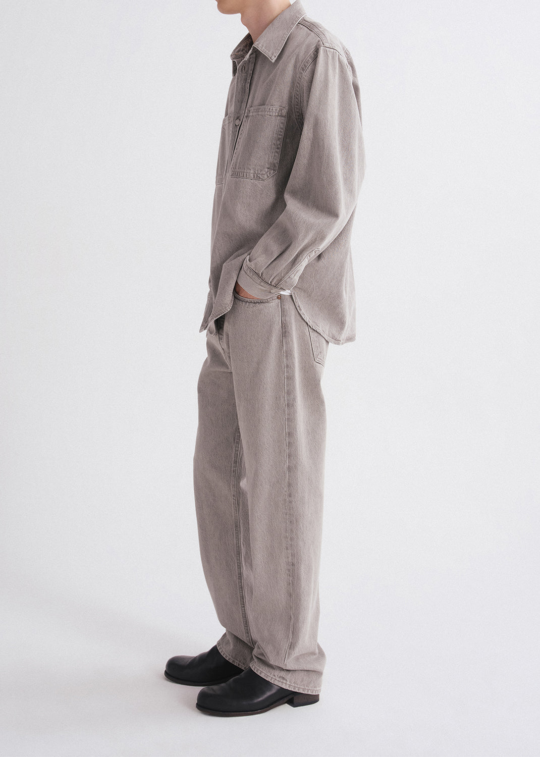 Person wearing a gray outfit with a shirt and pants on a grey background
