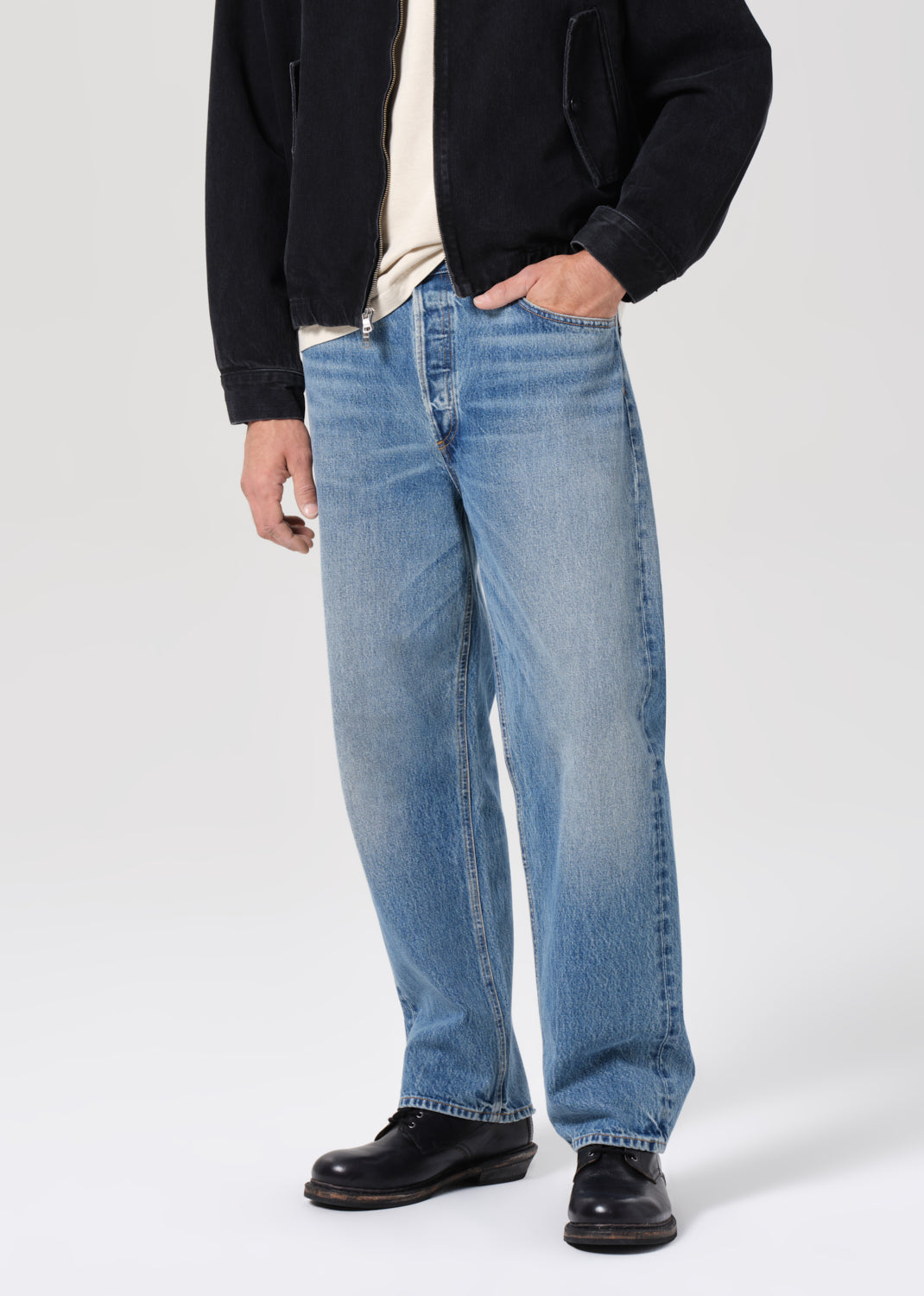 Person wearing blue jeans with a plain background