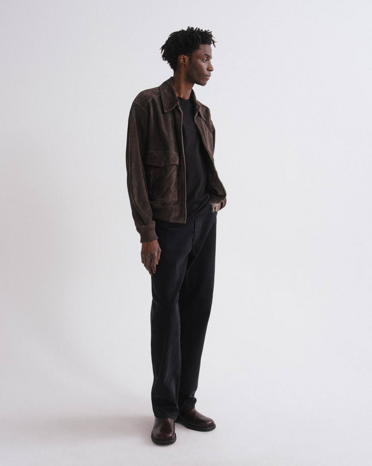Man wearing a brown jacket and black pants on a white background