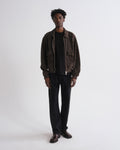 Man wearing a brown jacket and black pants on a white background
