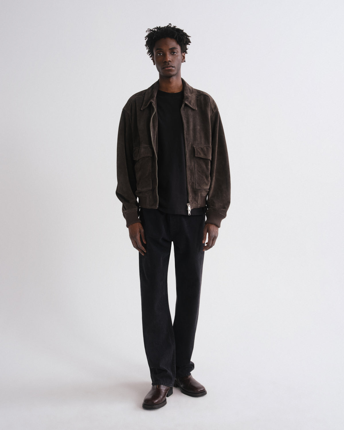 Man wearing a brown jacket and black pants on a white background