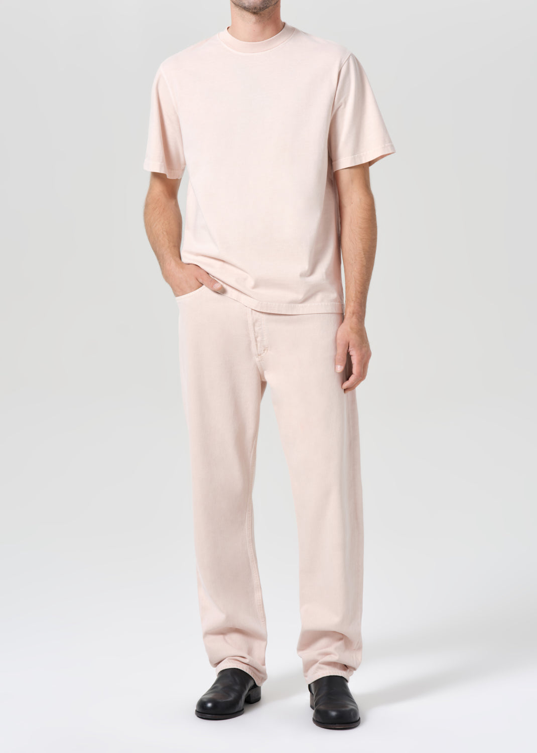 Person wearing a light pink t-shirt and pants on a white background