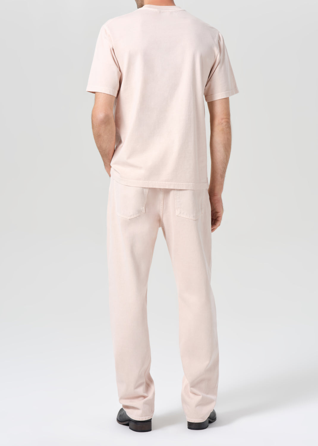 Person wearing a light pink t-shirt and pants on a white background