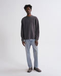 Man wearing a dark gray sweater and light blue jeans on a white background