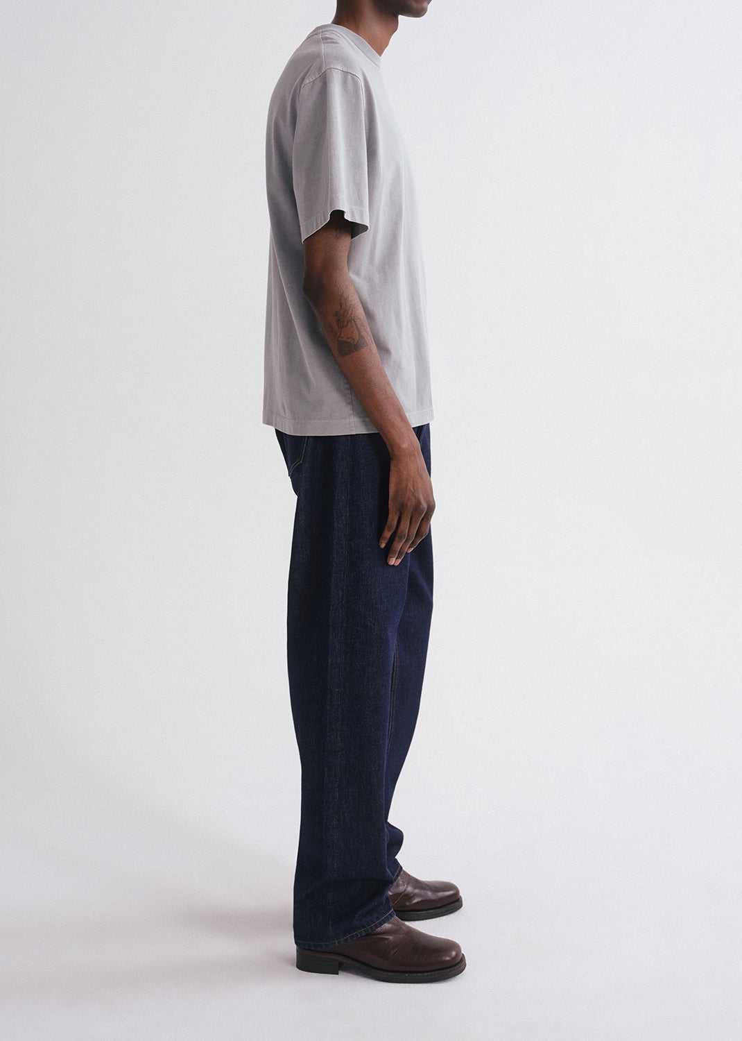 Person wearing a grey t-shirt and dark pants on a grey background