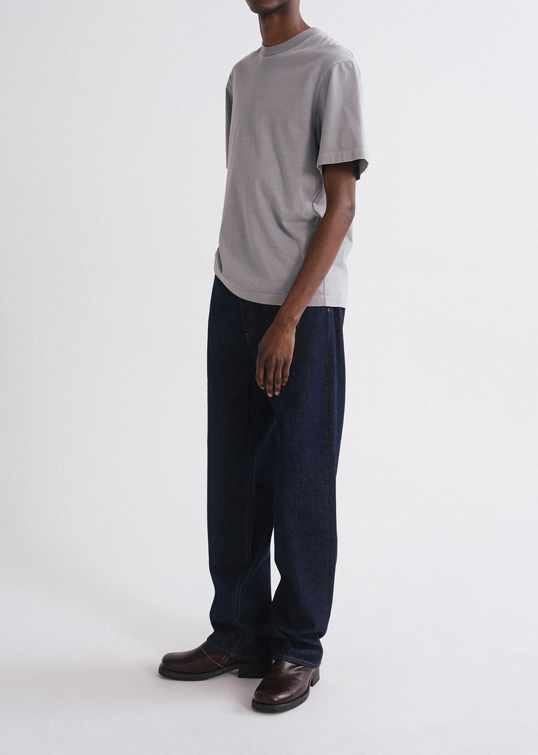 Person wearing a grey t-shirt and dark pants on a grey background