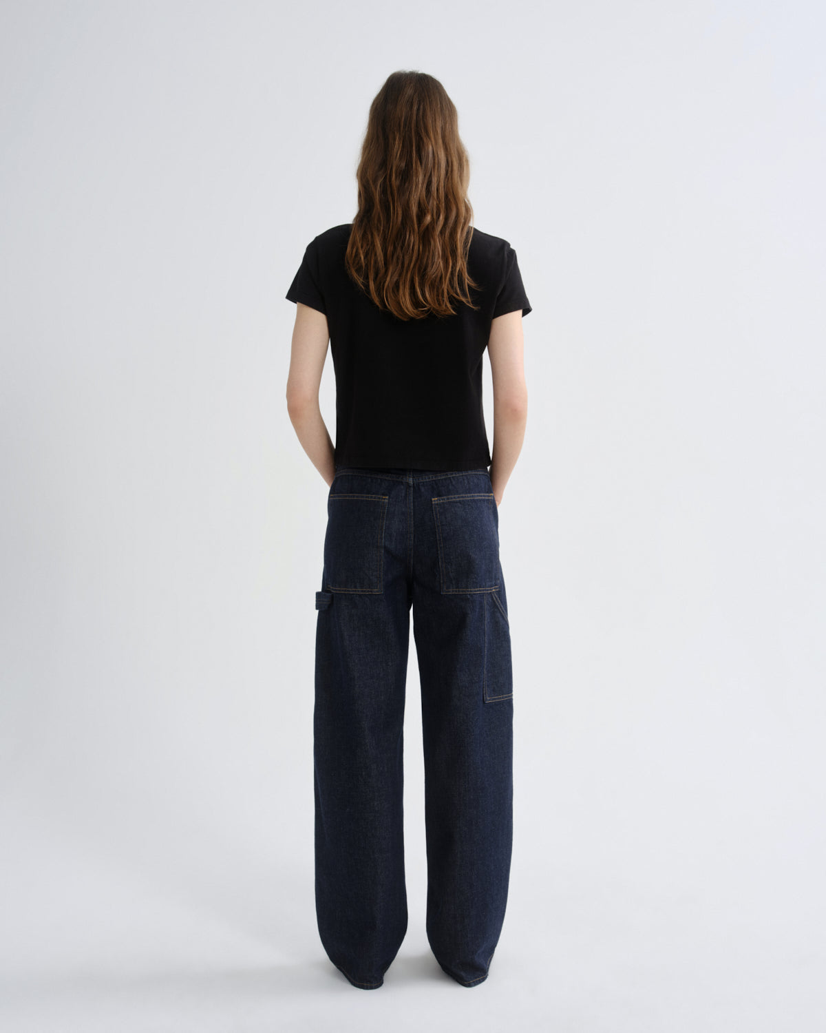 Person wearing dark blue jeans and a black t-shirt on a white background