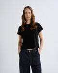 Person wearing a black t-shirt and dark jeans on a white background